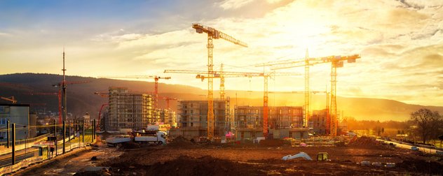 Baustelle mit mehreren Kränen bei Sonnenuntergang